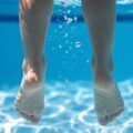 Подводная съемка ног в бассейне как символ обучения плаванию с мужем
