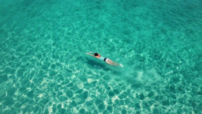Человек плывет в прозрачной воде океана