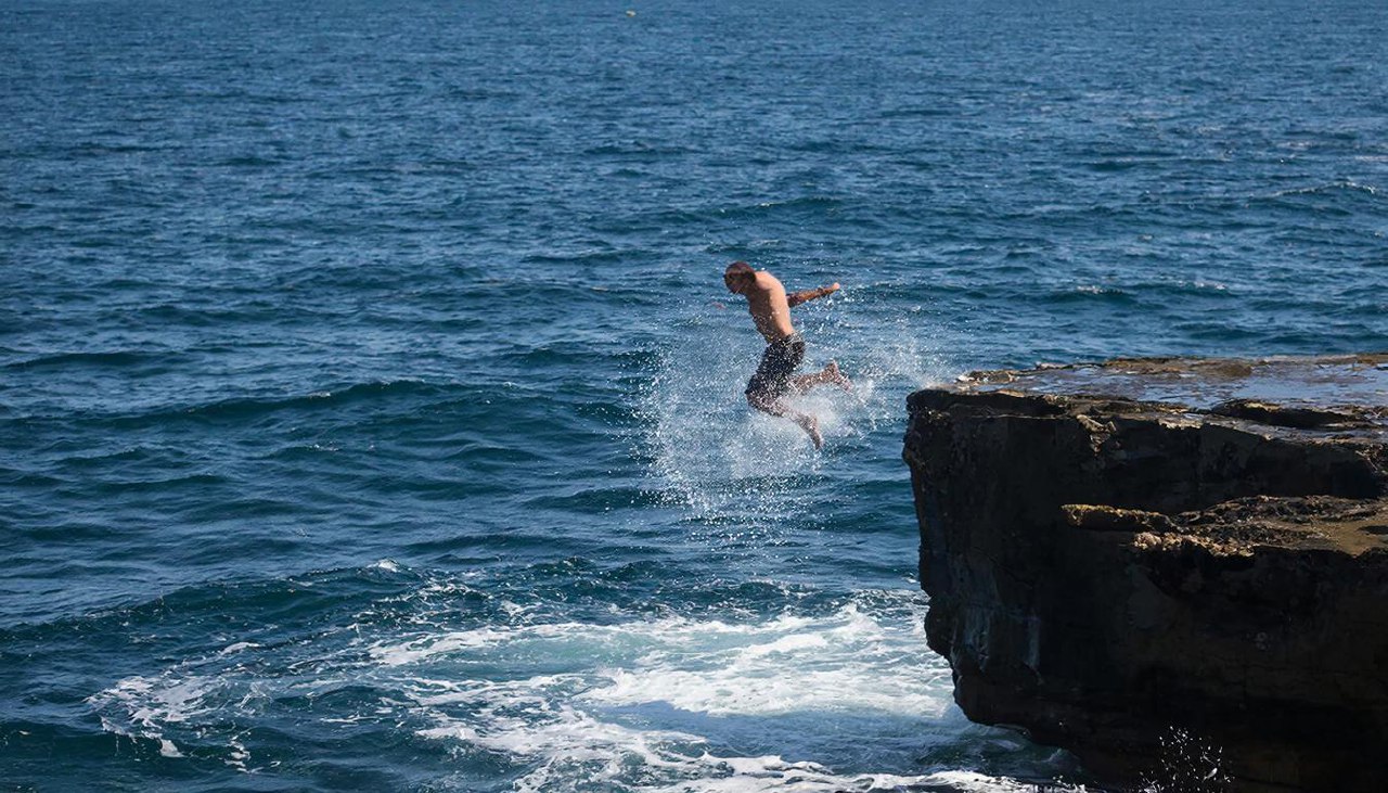 Человек прыгает в море со скалы во сне