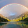 Магическая двойная радуга над горами и озером в лучах заката